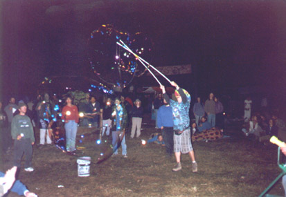 Bubble fans hold flashlights on bubbles without aiming into anyones eyes. In darkness every light source speckles the bubbles with dancing lights. The camera flash on the surroundings makes the edges of the bubbles visible.